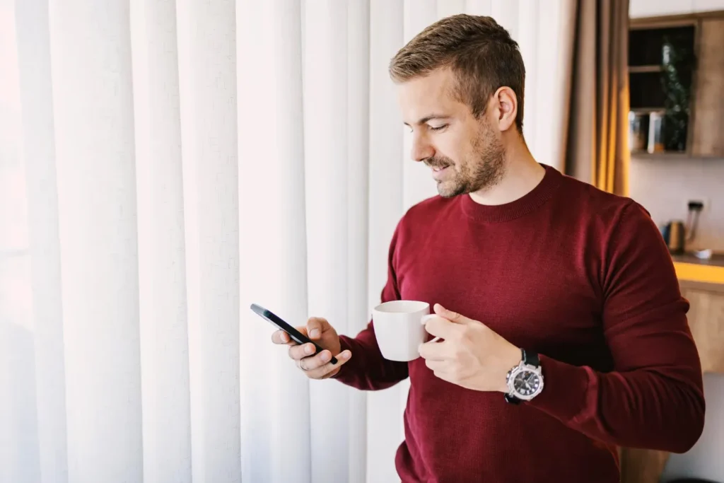 man reading email on phone with coffee