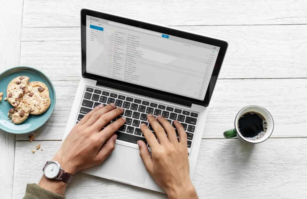 man at computer with coffee and cookie working on email subject lines