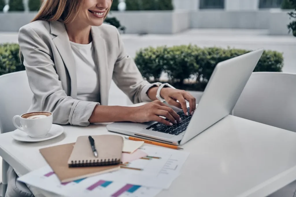 professional woman at computer with coffee smiling and working on email