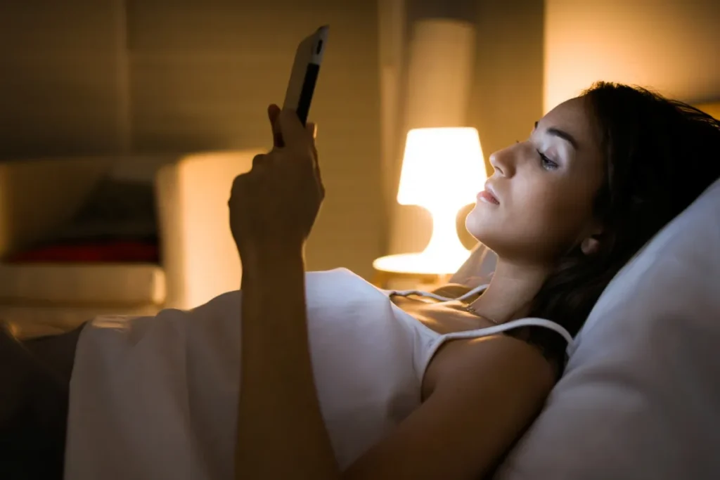 woman reading in bed with phone on dark mode