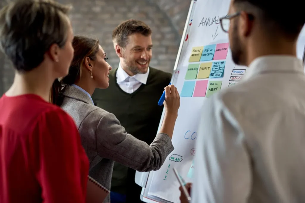 Team standing around a whiteboard strategizing for their email marketing campaign as a plan for the future