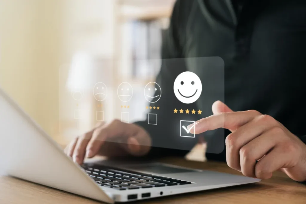 Person sitting at a computer with an email, graphic showcasing. Customer satisfaction popped up and they are touching the five star, one with the smiley face and a checkbox.